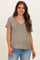 woman wearing a taupe v-neck maternity t-shirt and distressed blue jeans, smiling with a casual look