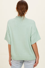 woman wearing a mint green short sleeve sweater with a relaxed fit and ribbed hem, seen from the back
