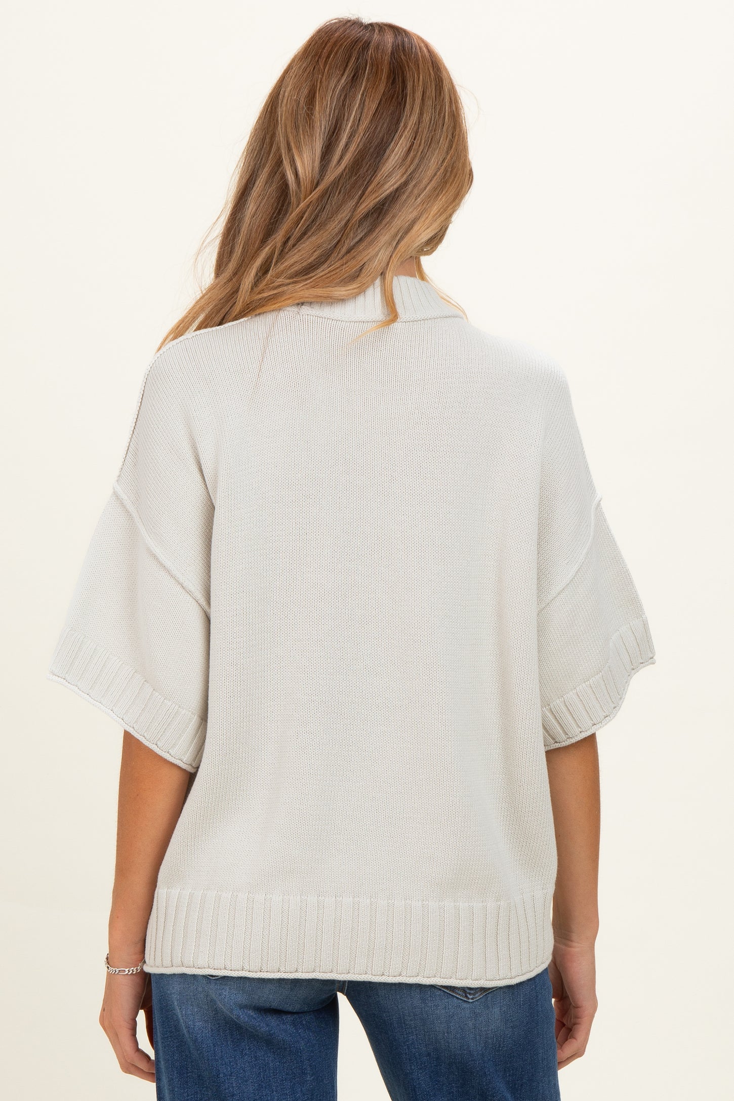 maternity wear in light beige knit sweater with wide sleeves and ribbed hem, shown from the back