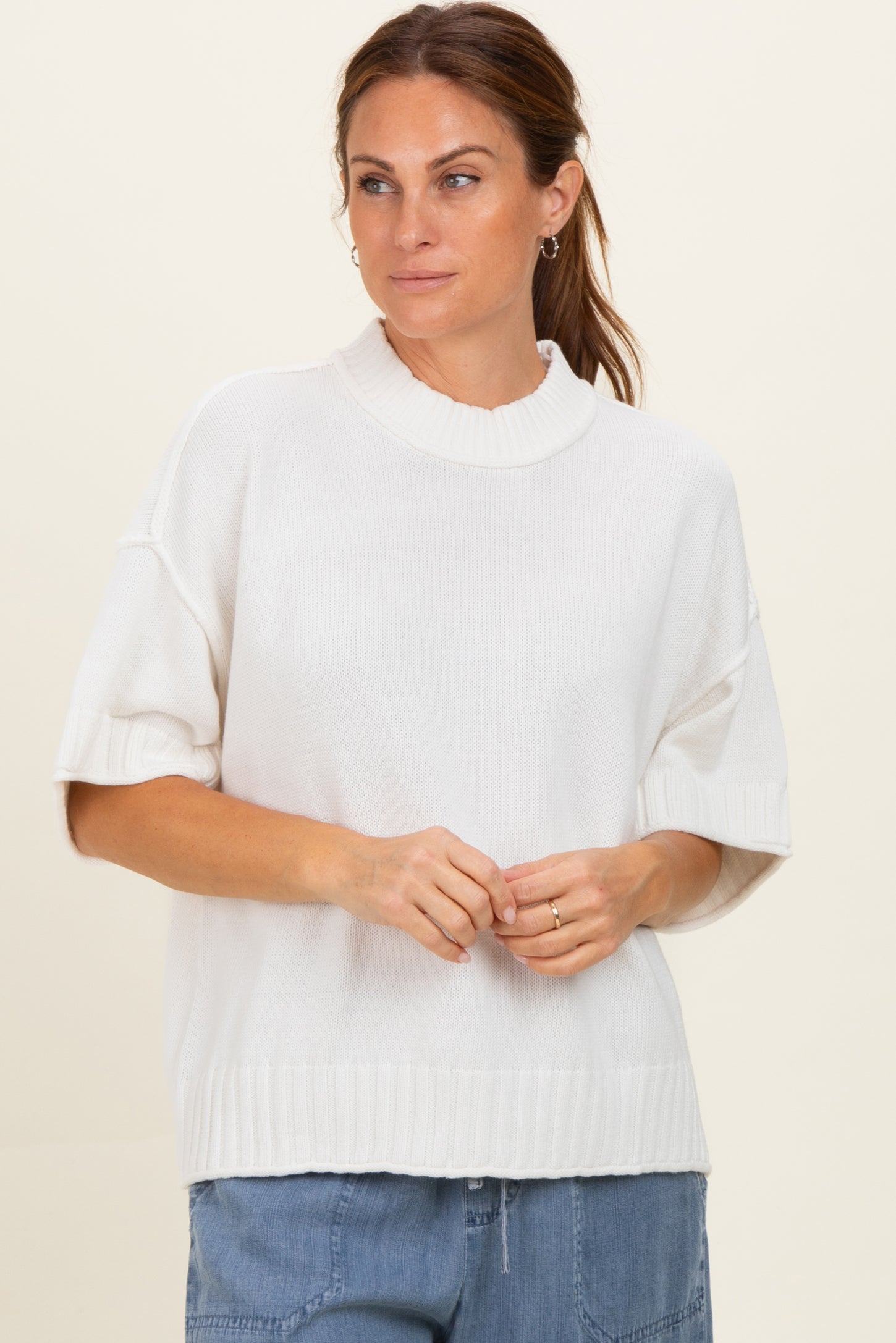 woman wearing a white short sleeve oversized knit sweater with a high neckline and relaxed fit