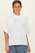 woman wearing a white oversized short sleeve sweater with a ribbed hem and mock neckline