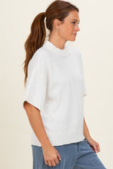 woman wearing a white short sleeve sweater with a high neckline and relaxed fit