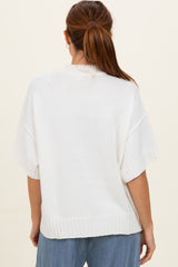 woman wearing a loose-fitting white knitted sweater with short sleeves and a ribbed hem, viewed from the back