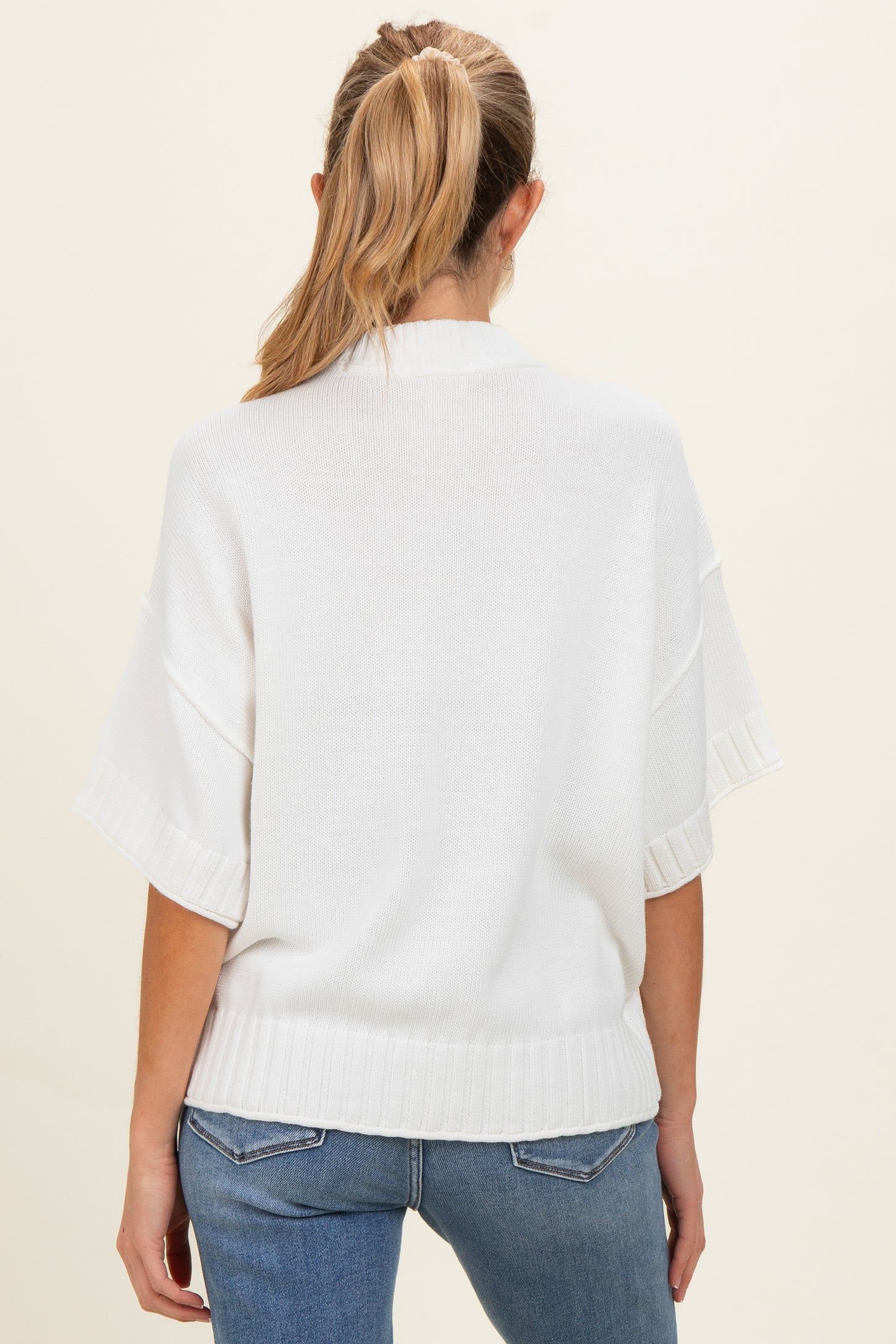 woman wearing a white oversized maternity sweater with short sleeves, shown from the back