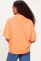 woman wearing an oversized orange sweater with short sleeves and a ribbed hem, view from the back