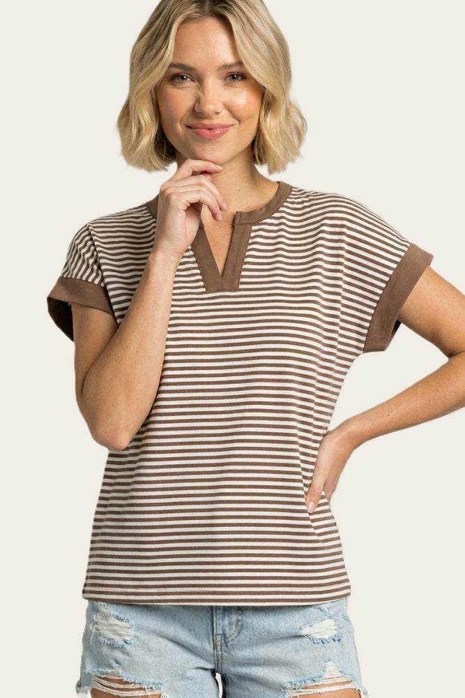 woman wearing a brown and cream striped short sleeve top with a henley neckline and rolled cuffs