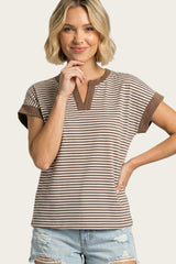 woman wearing a brown and cream striped short sleeve top with a henley neckline and rolled cuffs