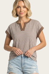 woman wearing a brown and cream striped short sleeve top with a v-neckline and rolled cuffs, styled with distressed denim shorts