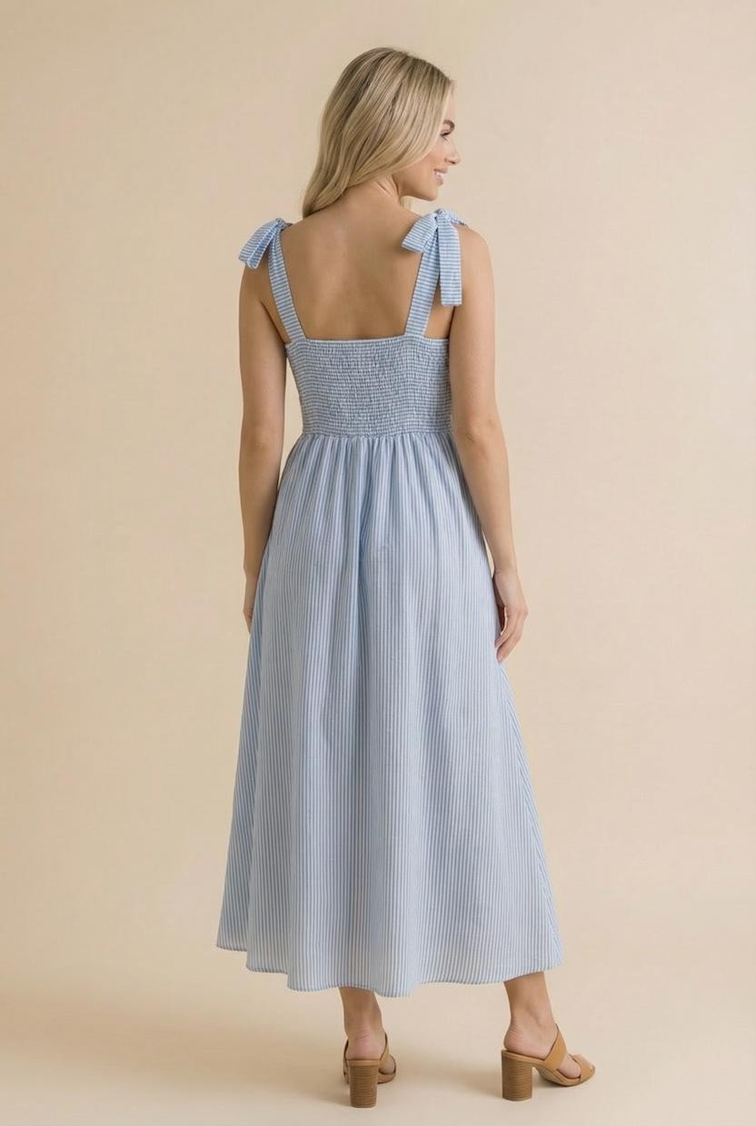 woman wearing a blue and white striped maxi dress with shoulder ties and smocked bodice, shown from the back