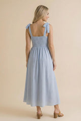 woman wearing a blue and white striped maxi dress with shoulder ties and smocked bodice, shown from the back