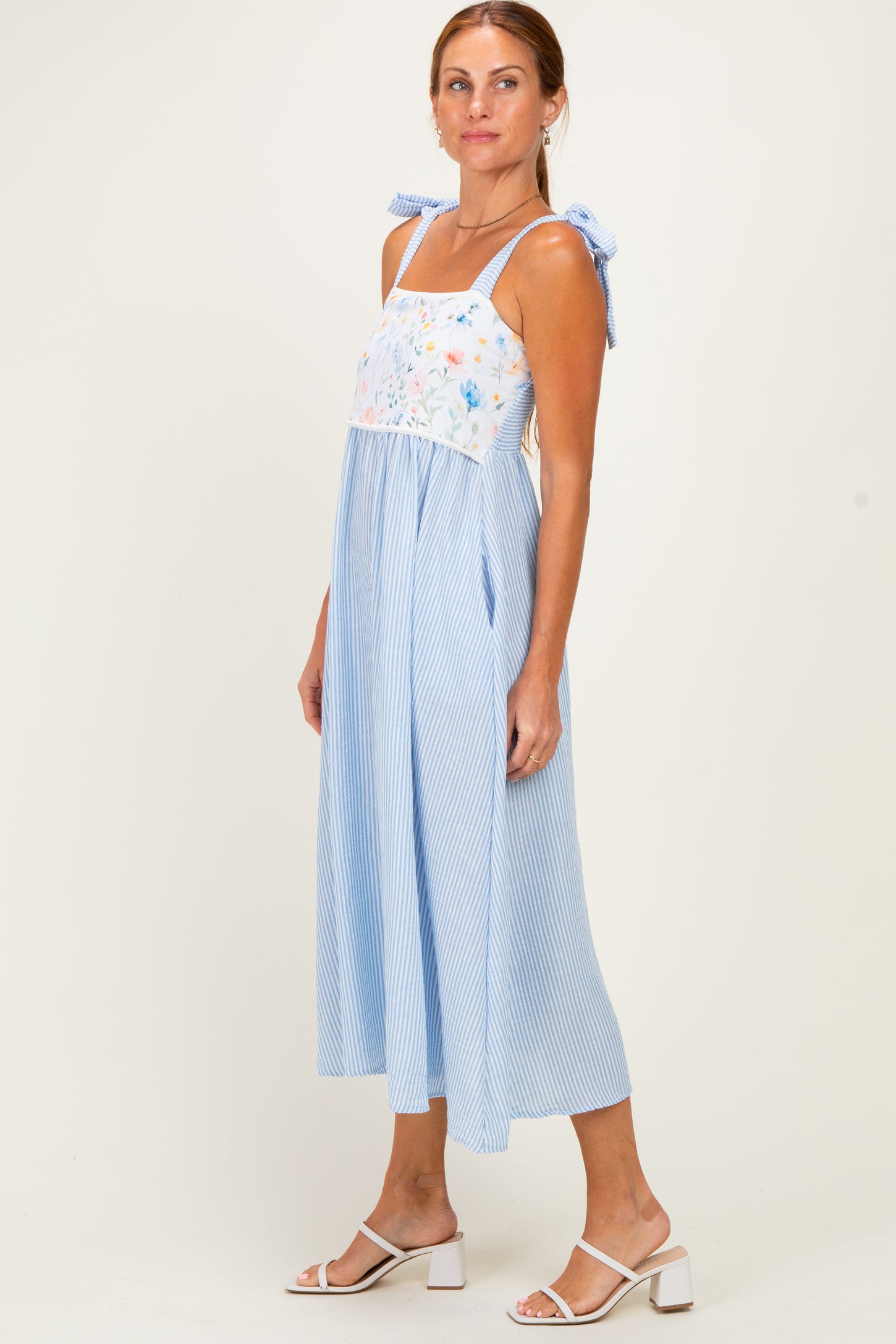 woman wearing a blue and white striped midi dress with floral embroidery and adjustable shoulder ties