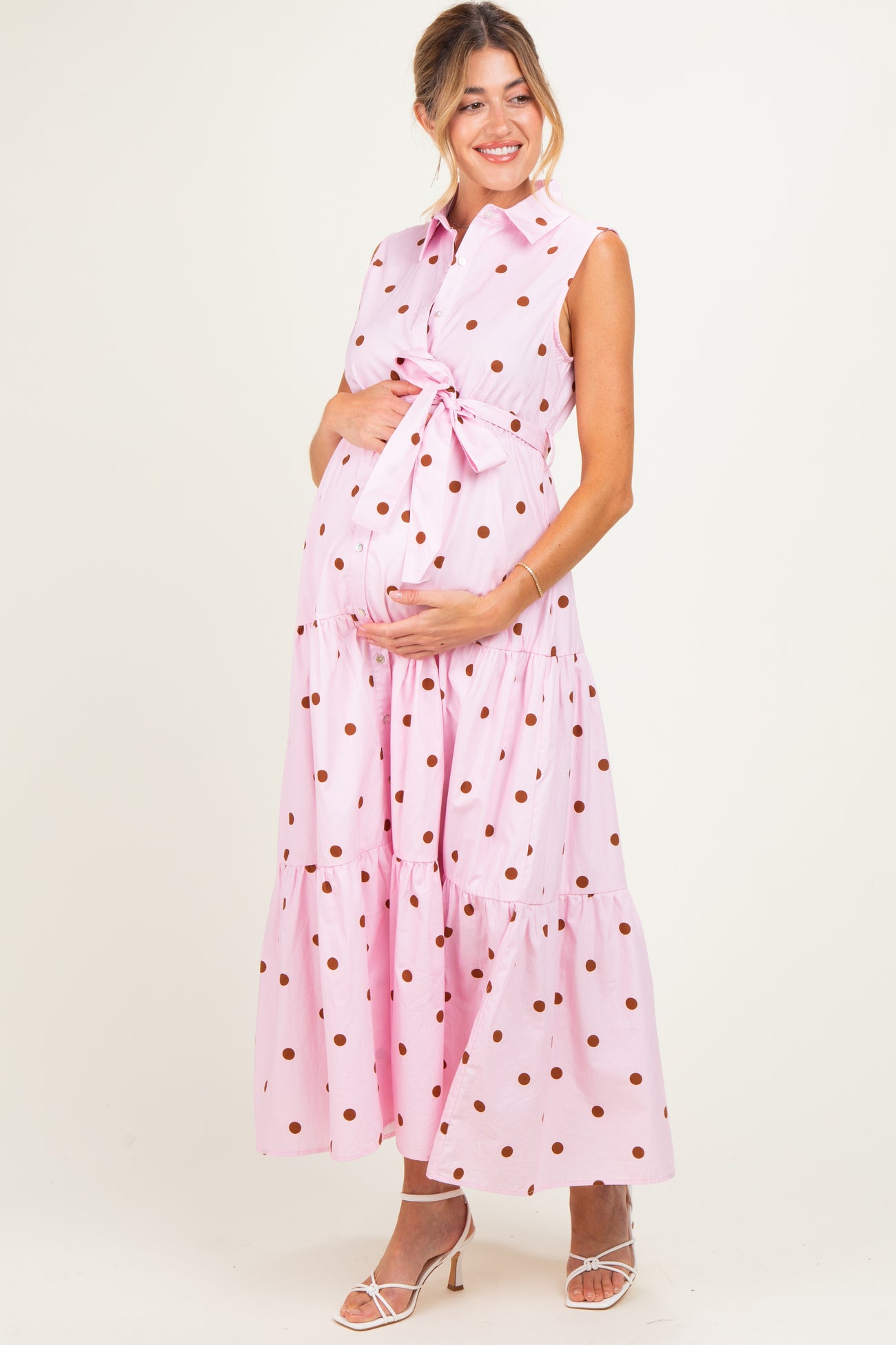 woman wearing a pink polka dot maternity maxi dress with a tied waist and showing her baby bump