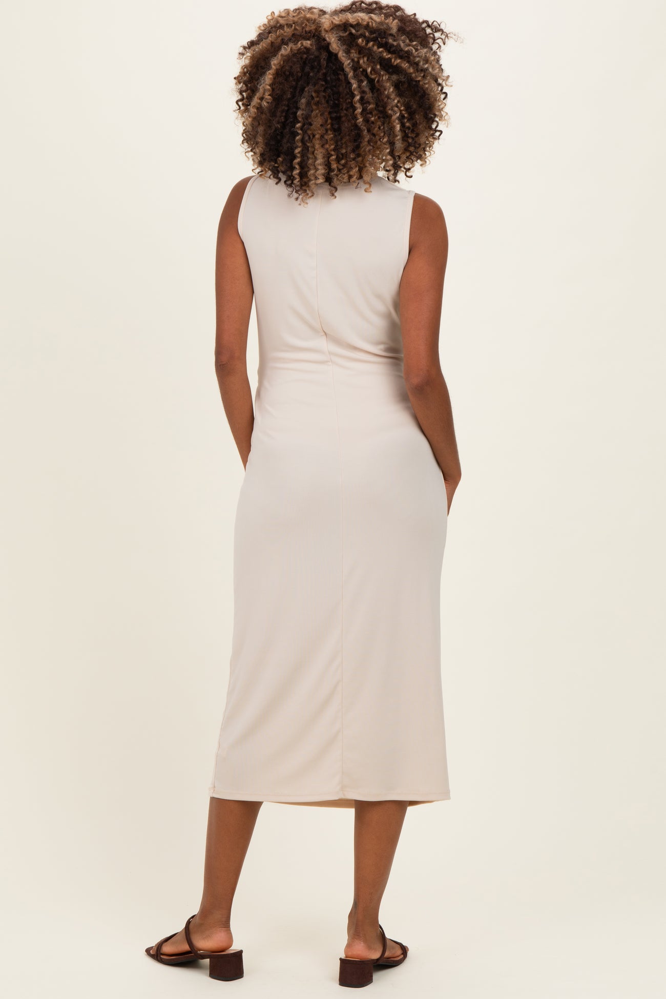 woman wearing a beige maternity dress with a fitted silhouette, shown from the back