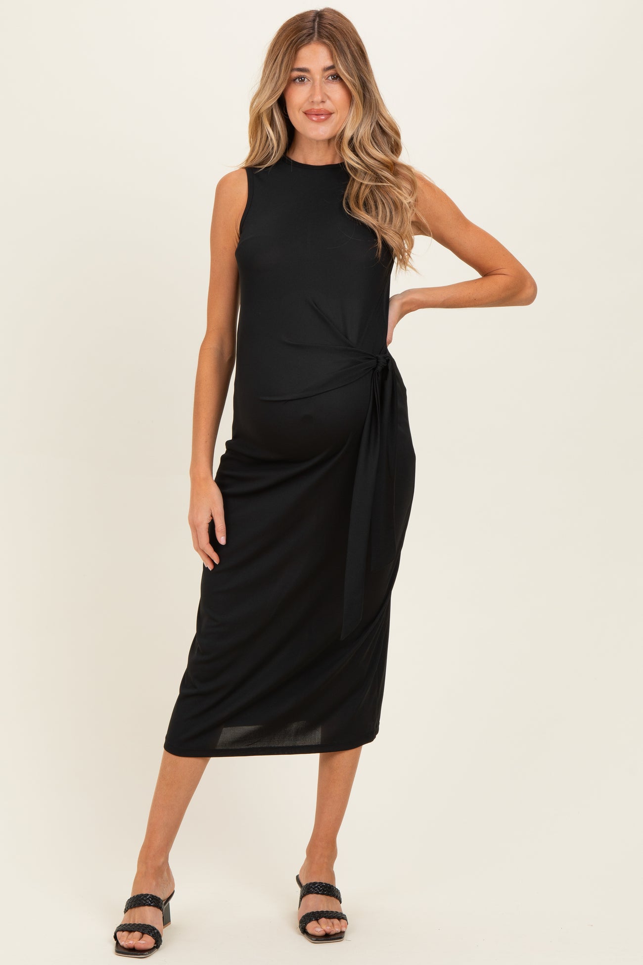 woman wearing a black sleeveless maternity midi dress with a side tie and a visible baby bump