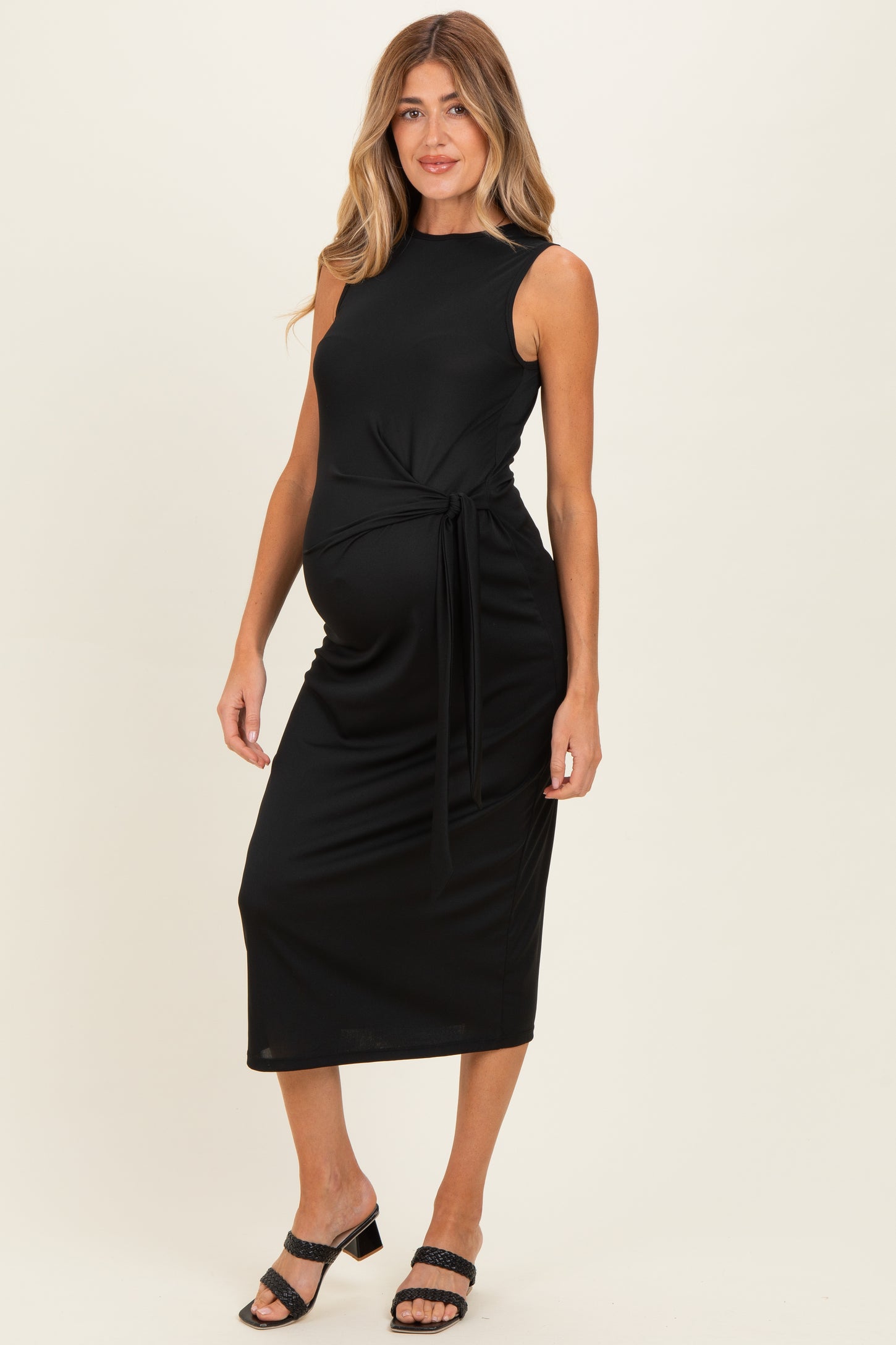 woman wearing a black sleeveless maternity dress with a tied waist and visible baby bump
