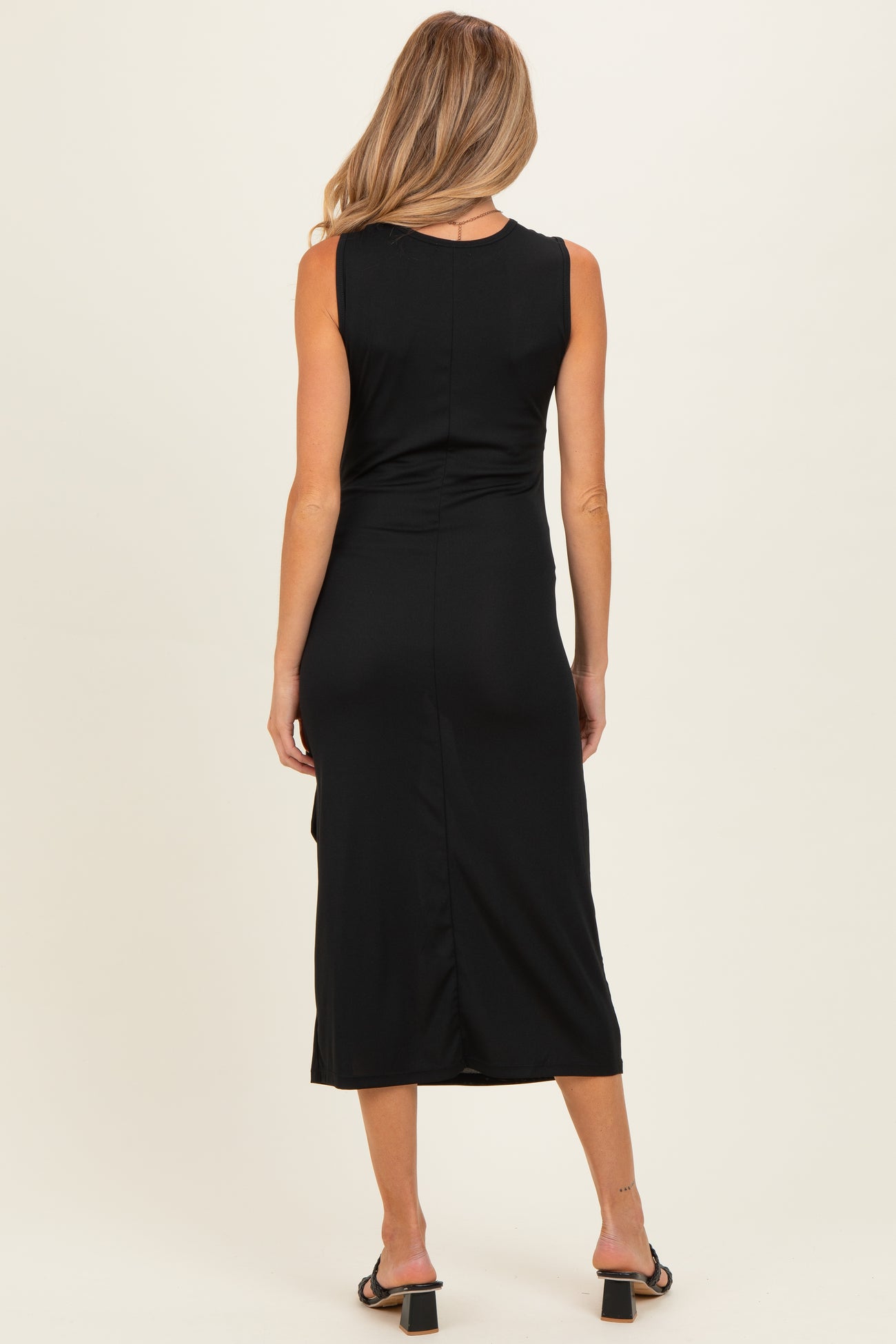 woman wearing a black sleeveless maternity dress with a mid-length hem and a slit at the back