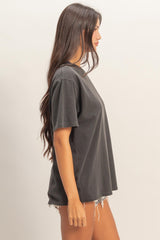 woman wearing a loose fit black t-shirt with a crew neckline and distressed denim shorts