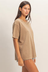 woman wearing a loose-fitting tan oversized t-shirt paired with distressed denim shorts