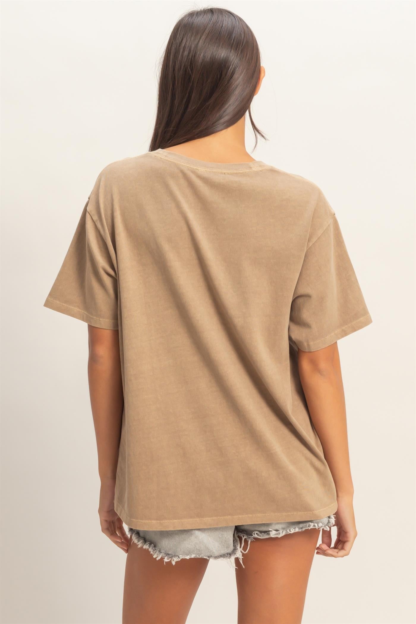 woman wearing a relaxed fit brown oversized t-shirt with short sleeves and back view, paired with denim shorts