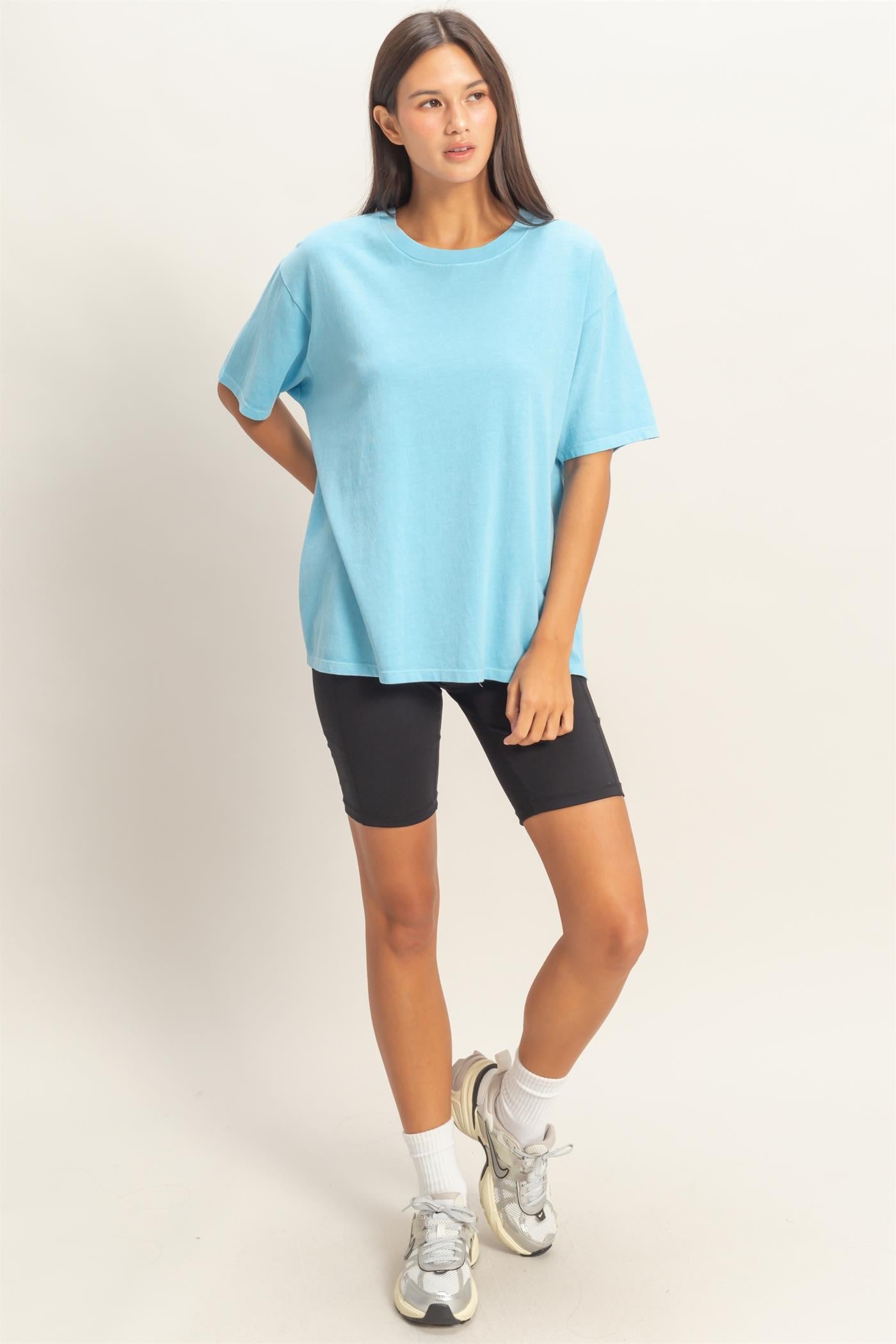woman wearing a light blue oversized t-shirt and black bike shorts, styled with sporty sneakers and white ankle socks