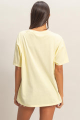 woman wearing a yellow oversized t-shirt, seen from the back, with short sleeves and a relaxed fit