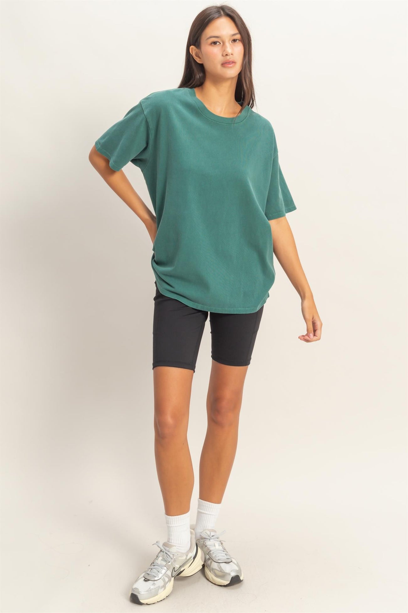 woman wearing a green oversized t-shirt and black bike shorts with white socks and sneakers
