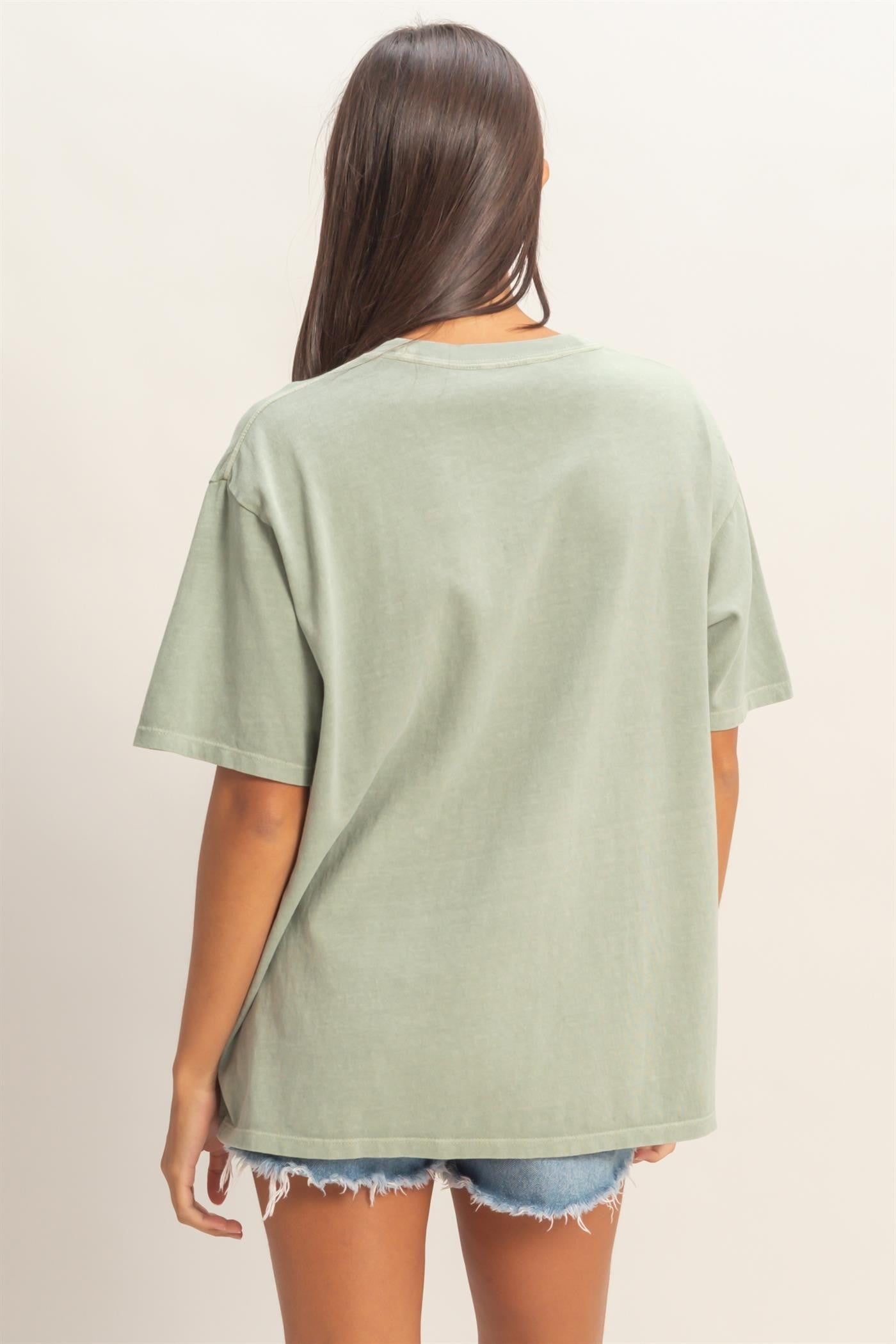 woman wearing a relaxed fit green oversized t-shirt with short sleeves and back view, paired with denim shorts
