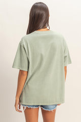 woman wearing a relaxed fit green oversized t-shirt with short sleeves and back view, paired with denim shorts