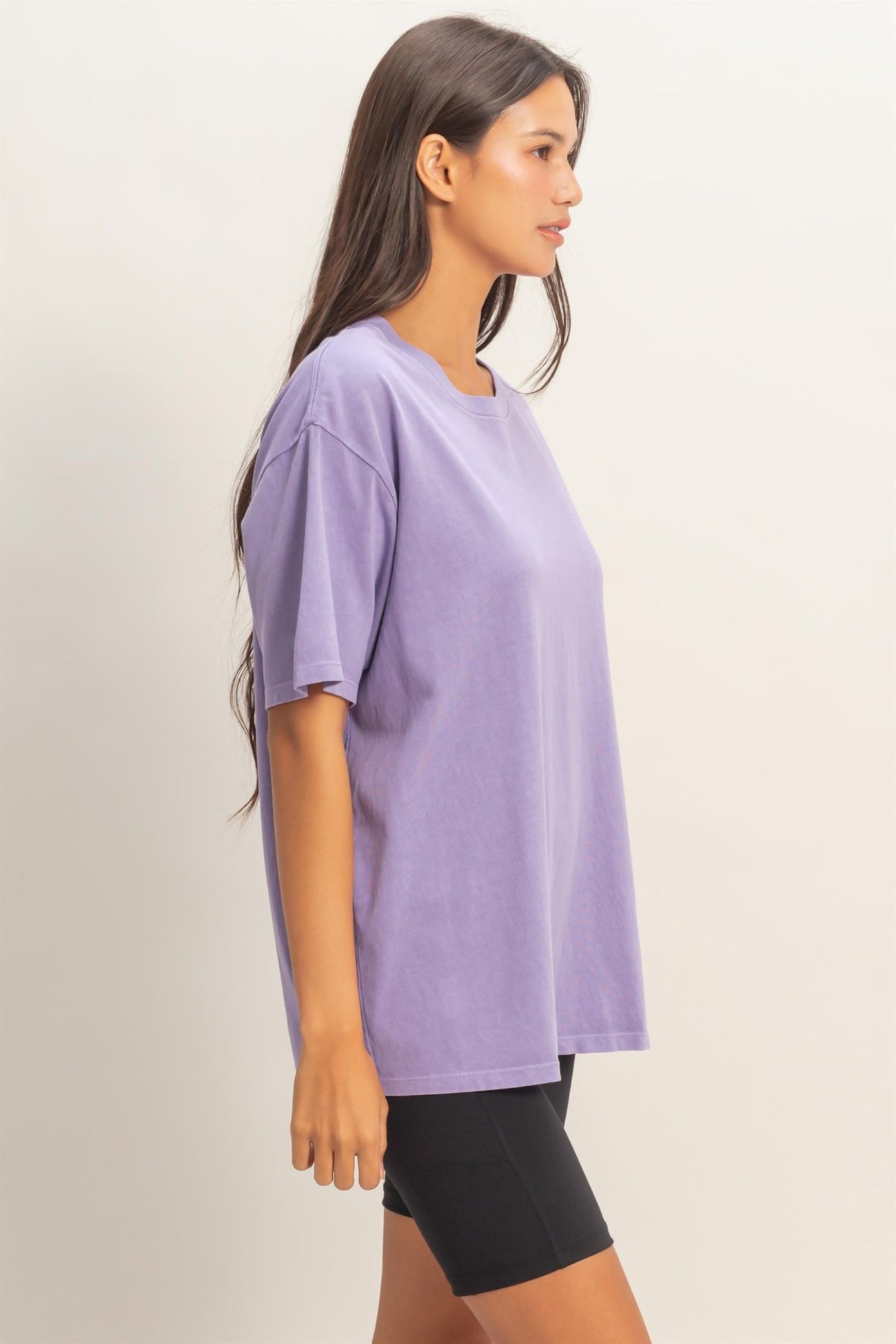 woman wearing a loose-fitting purple oversized t-shirt with short sleeves and black biker shorts