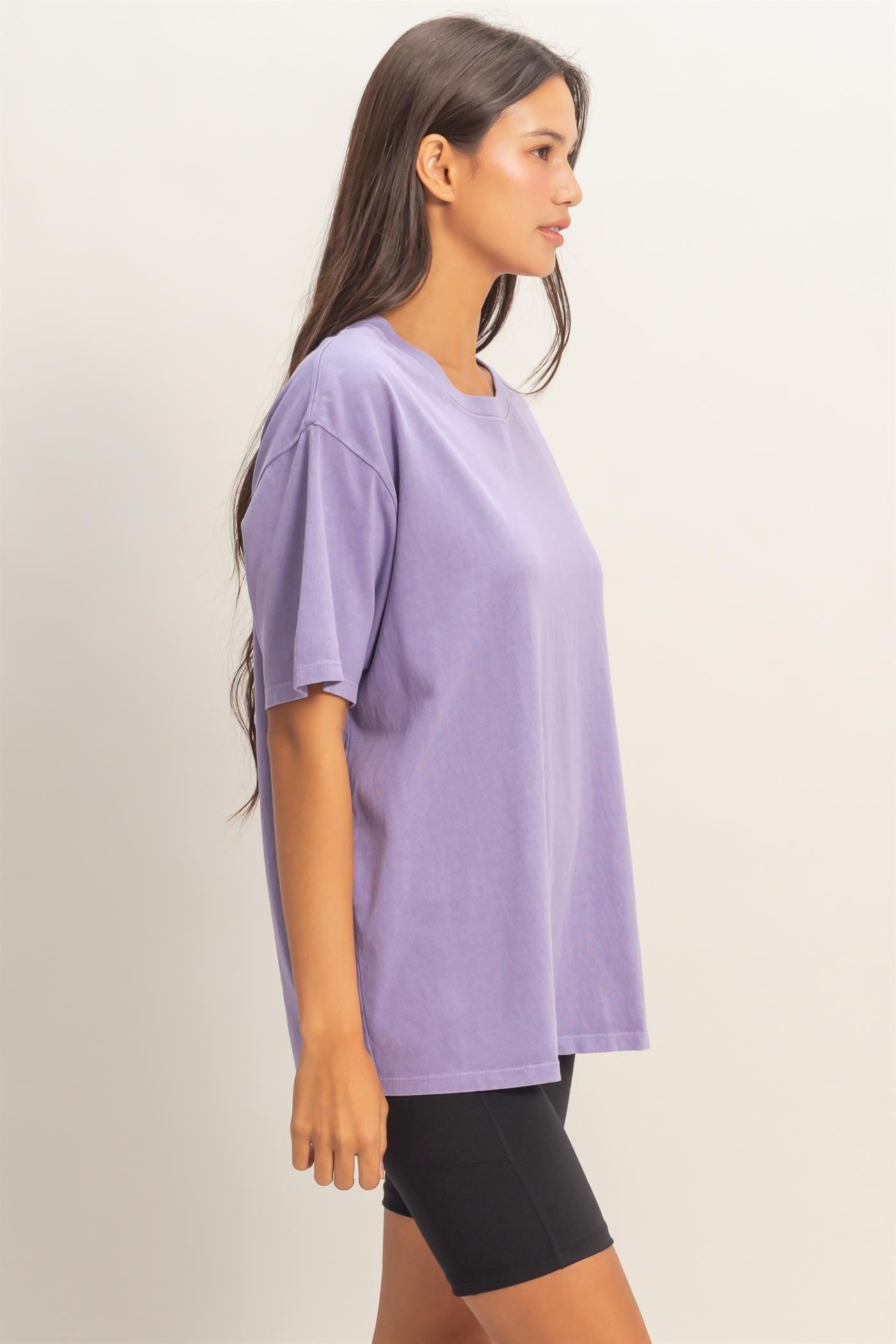 woman wearing a loose-fitting purple oversized t-shirt with short sleeves and black biker shorts