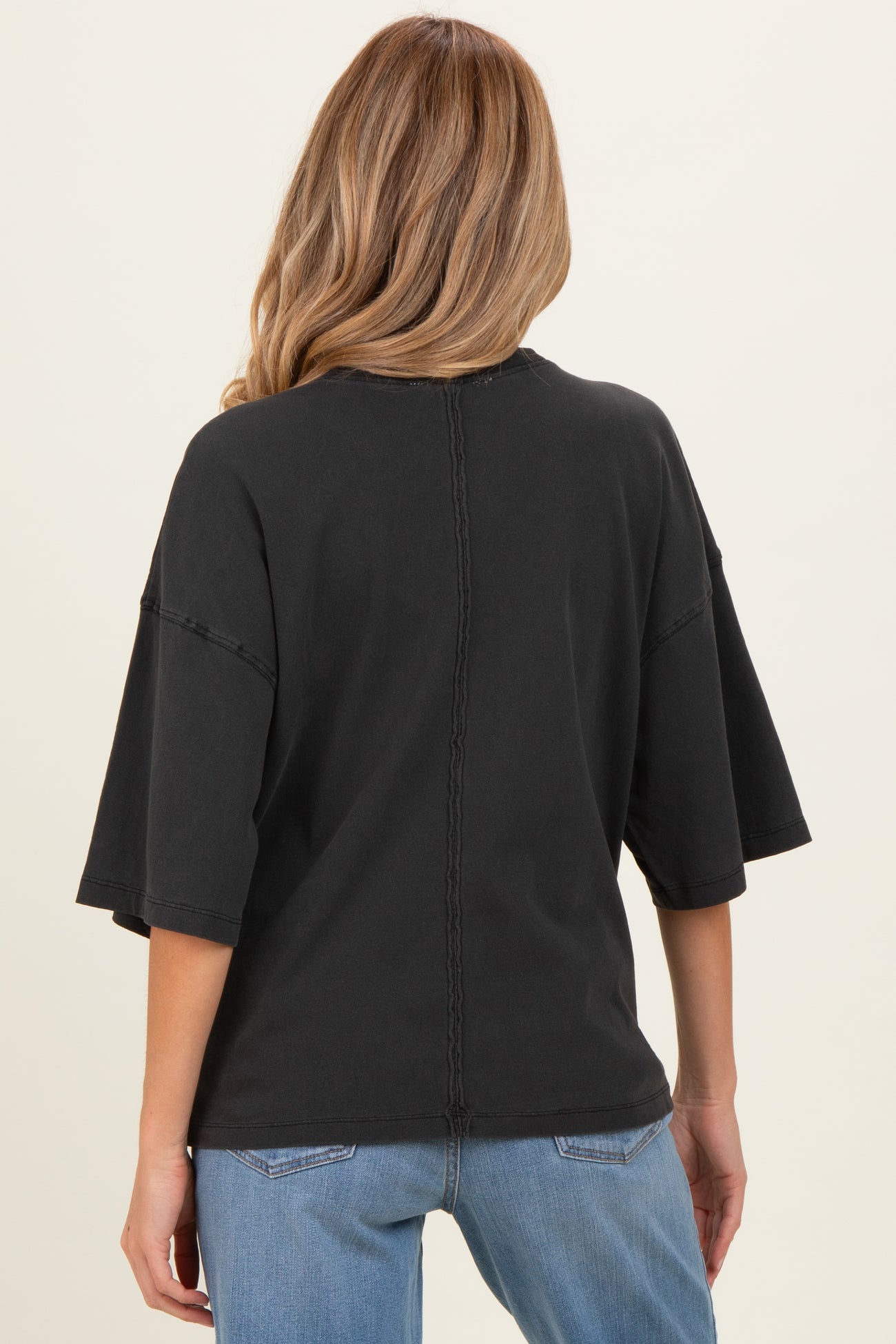 woman wearing a black oversized maternity top with cropped sleeves and back stitch detailing