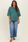 woman wearing a green oversized maternity t-shirt with short sleeves and blue wide-leg jeans