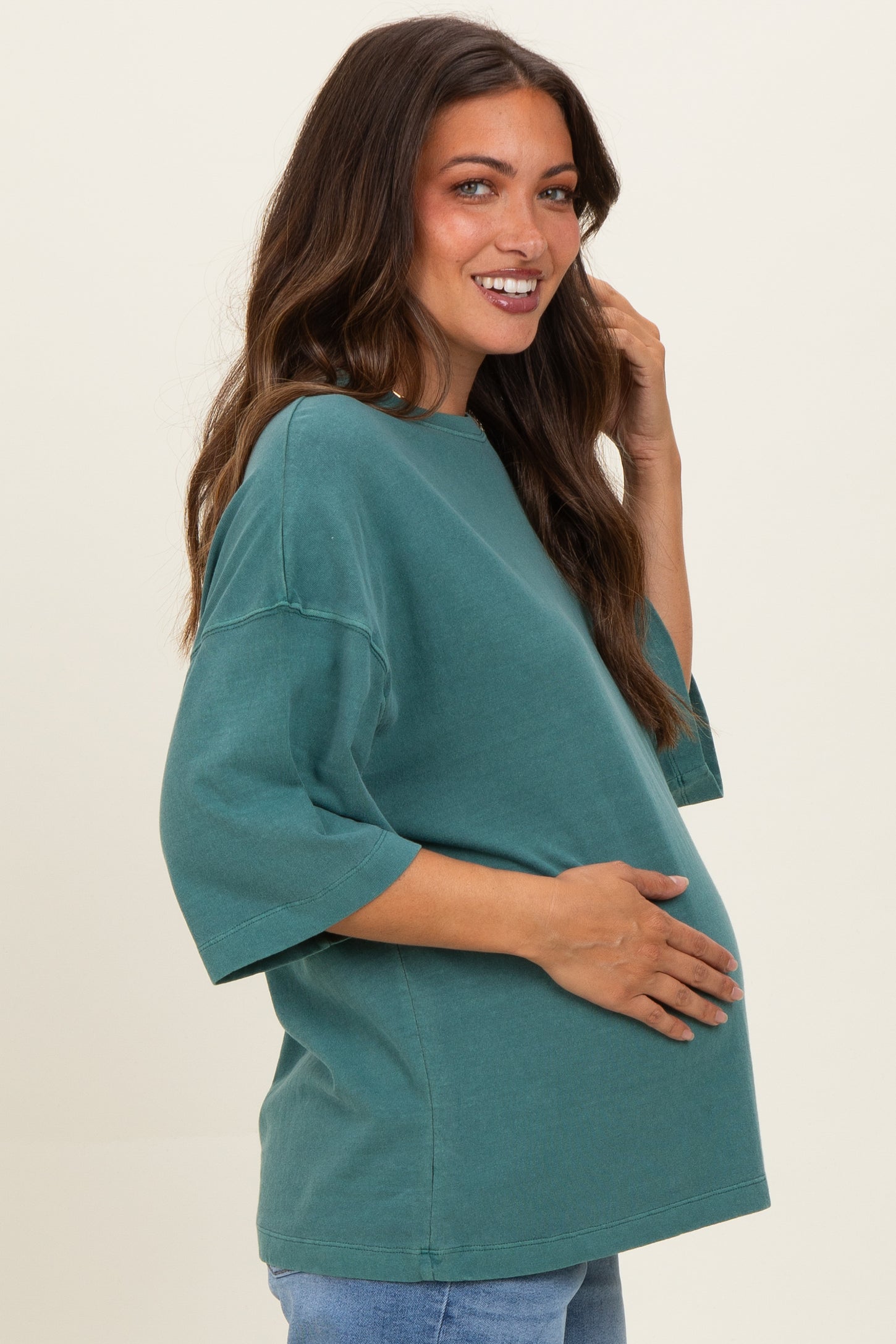 woman wearing a teal oversized maternity t-shirt and holding her baby bump