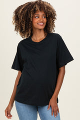 woman wearing a black oversized maternity t-shirt and blue jeans, with a visible baby bump