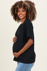 woman wearing a black maternity t-shirt and holding her baby bump, styled with loose sleeves and relaxed fit
