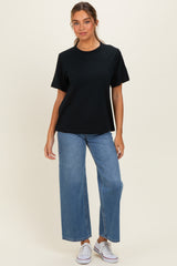 woman wearing a black oversized t-shirt with short sleeves and high-waisted wide-leg jeans, paired with white sneakers