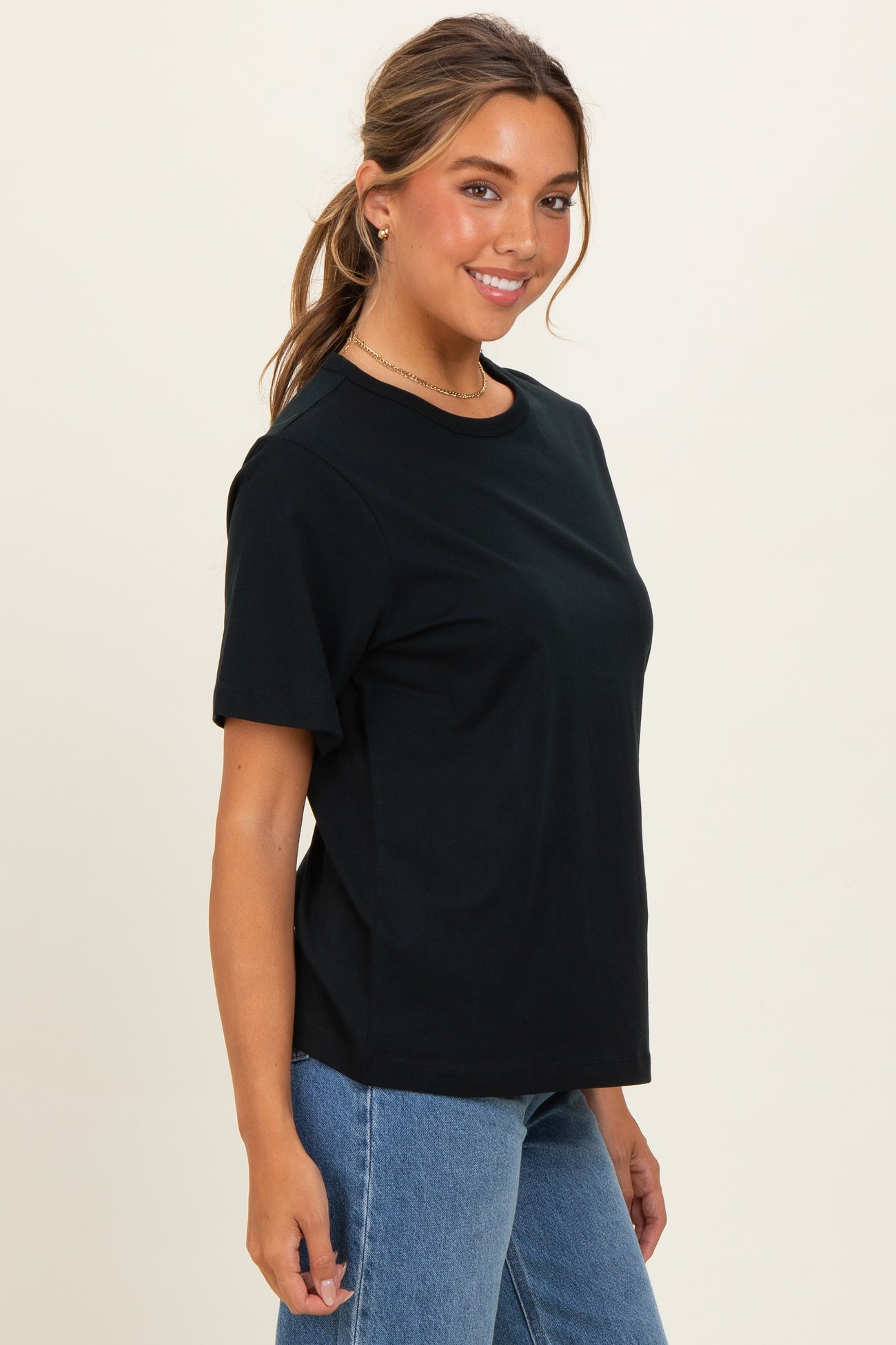 woman wearing a black short sleeve t-shirt and blue high-waisted jeans