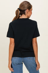 woman wearing a black short sleeve t-shirt and blue high-waisted jeans, viewed from the back