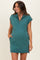 woman wearing a teal maternity dress with a zip neckline and short sleeves, featuring pockets