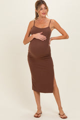 woman wearing a brown maternity dress with thigh-high slit and holding her baby bump