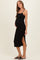 woman wearing a black maternity midi dress with side slits and spaghetti straps, showing her baby bump