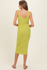 woman wearing a lime green ribbed maternity midi dress, showing a fitted silhouette from the back