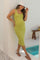 woman wearing a lime green ribbed maternity dress and a white bucket hat, holding her baby bump by a poolside