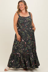 woman wearing a black floral print maternity plus maxi dress with a tiered skirt and pockets