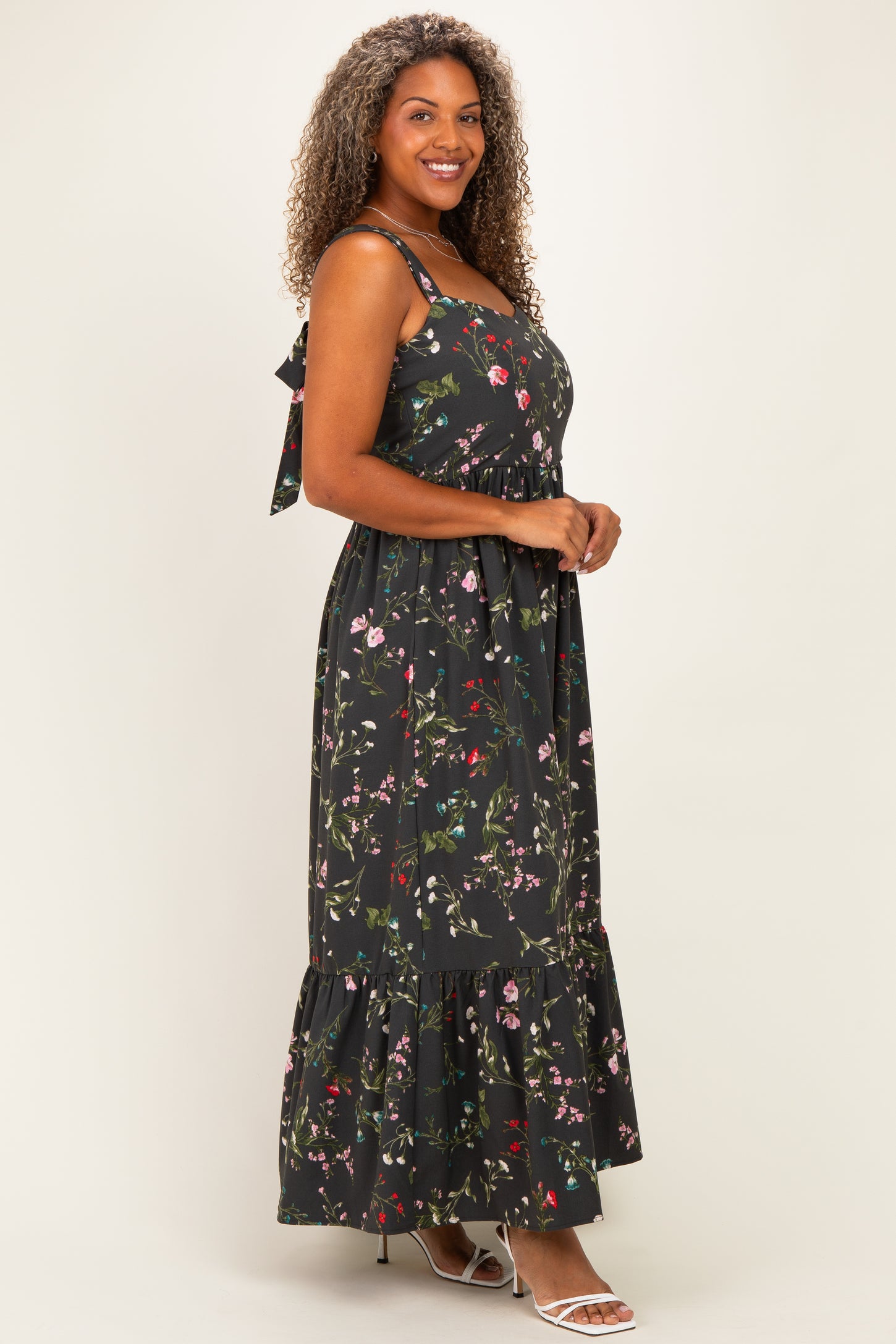 woman wearing a black floral maxi dress with spaghetti straps and a tiered hem