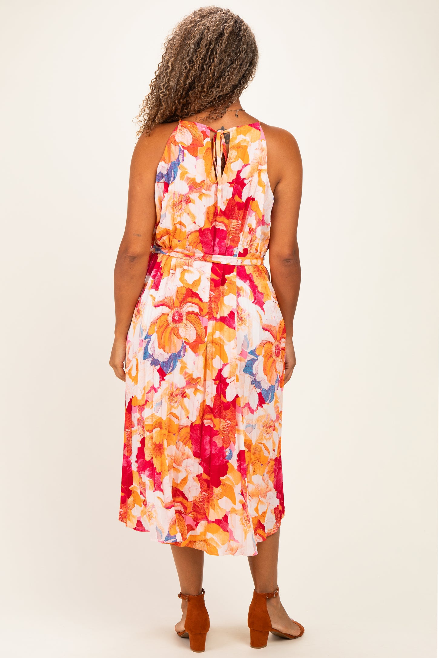 woman wearing a floral sleeveless plus-size maxi dress with a tie back and vibrant colors