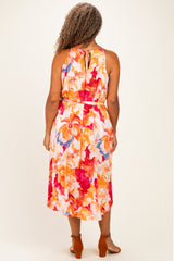 woman wearing a floral sleeveless plus-size maxi dress with a tie back and vibrant colors