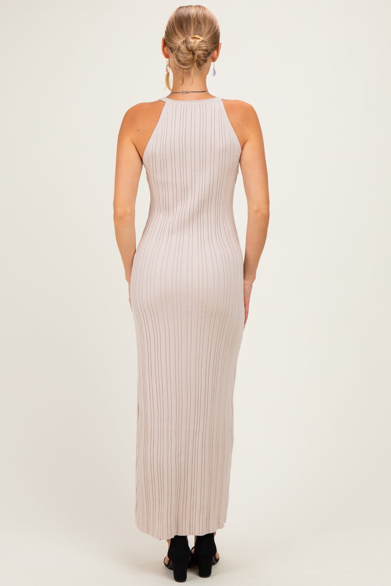 woman wearing a beige ribbed maxi dress with a halter neckline, seen from the back