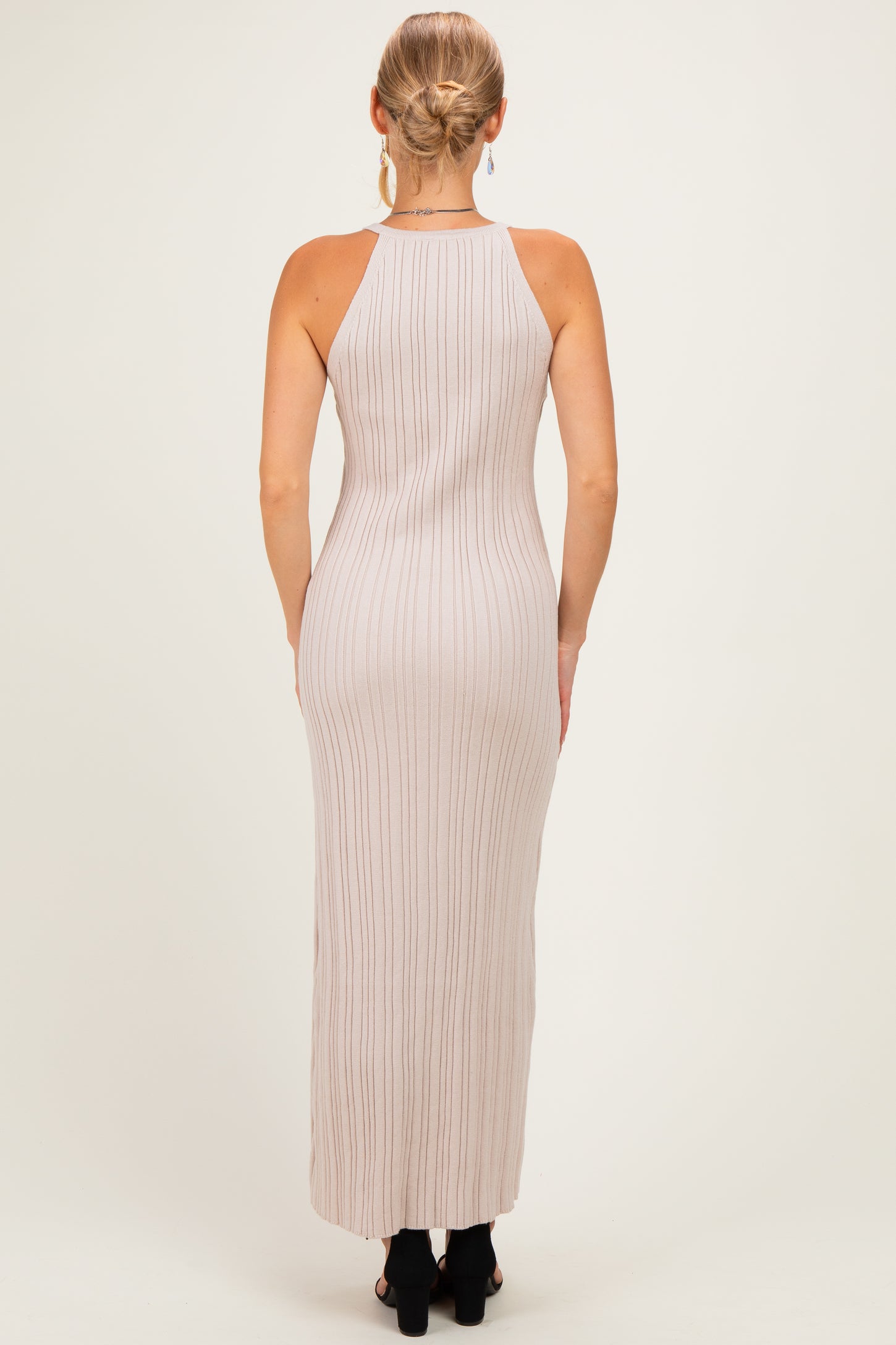 woman wearing a beige ribbed maxi dress with a halter neckline, seen from the back