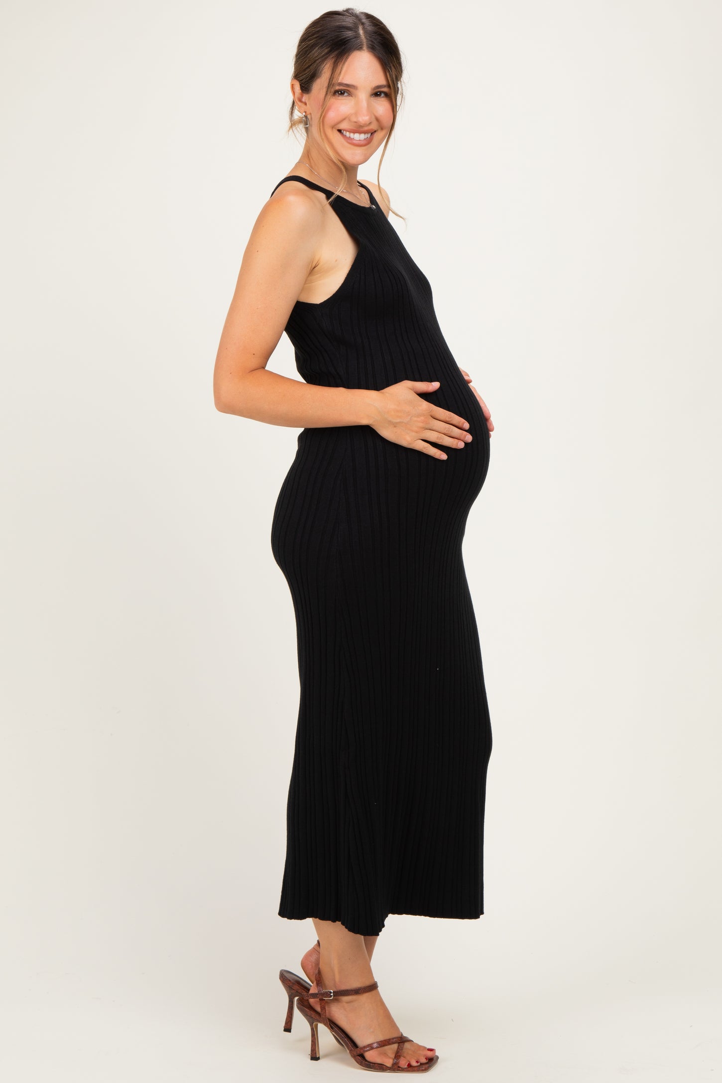 woman wearing a black ribbed maternity dress and showing her baby bump